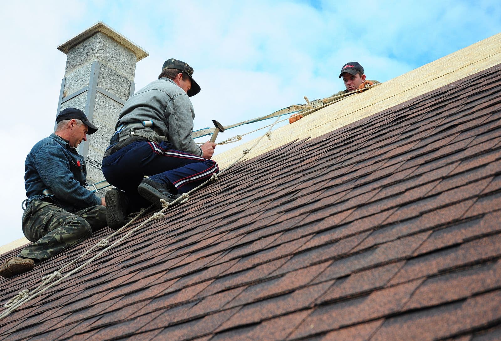 Roofing Contractors Install New House Roofing with Asphalt Shingles Roofing Construction. Roofers with safety rope.