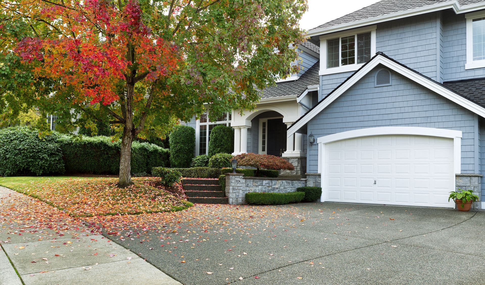 Front view of modern residential home during early autumn season in Northwest of United States. Maple trees beginning to change leaf colors.