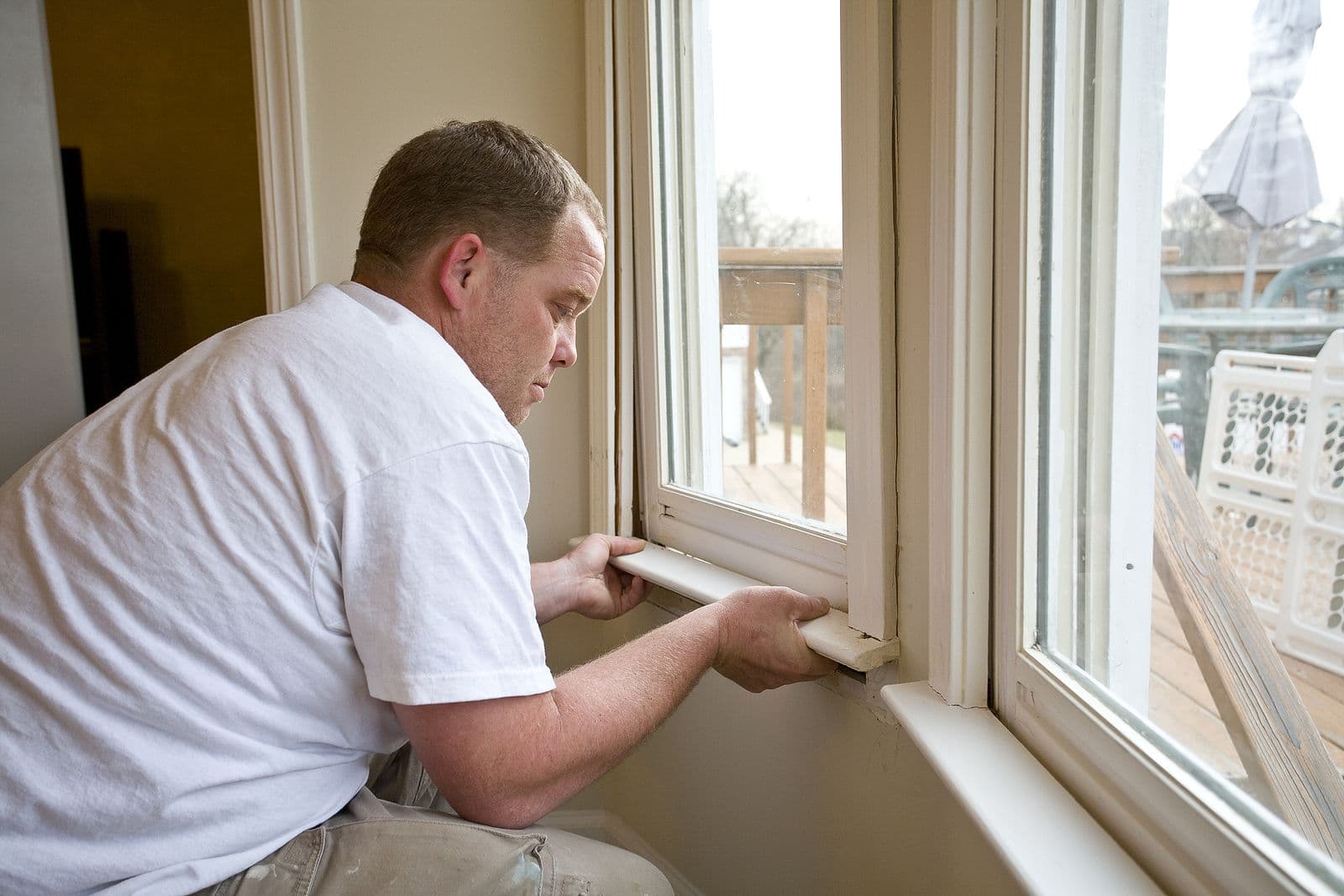 Carpenter repairing window frames home is being updated to be sold