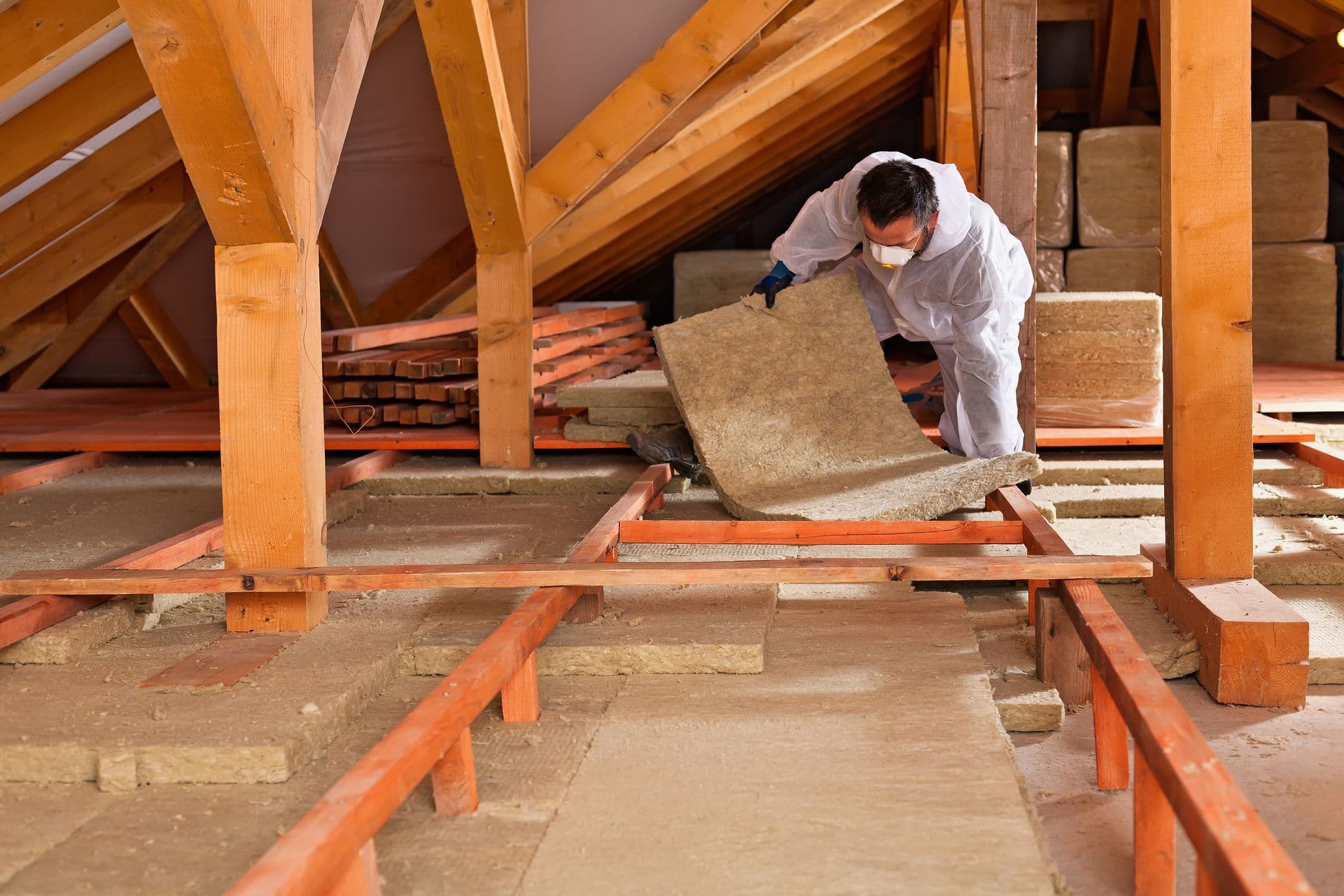 Man installing thermal insulation layer under the roof - using mineral wool panels