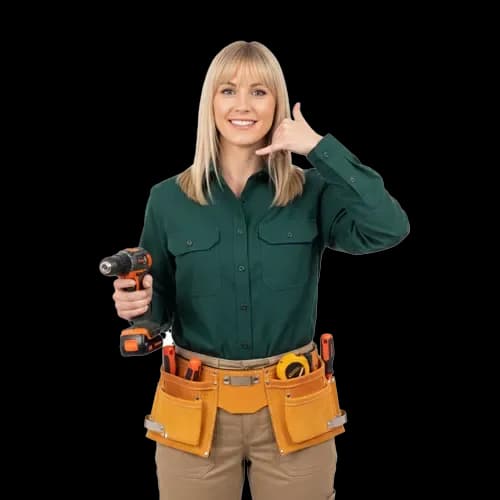 Studio portrait against a plain white background of a smiling blonde female contractor wearing a long-sleeved dark green button-up shirt, beige pants, and a tan leather tool belt. She holds a cordless power drill in her right hand and makes a "call me" hand gesture near her ear with her left hand.